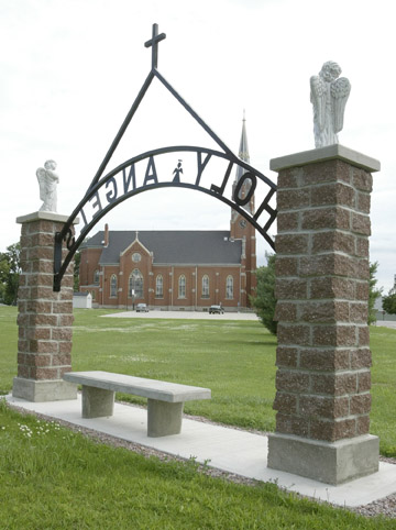 Newly-built entrance arch to the cemetary located north of Holy Angels Church in Roselle. The pyramid shaped arch mimics the arch visible on the north side of the church in the background.